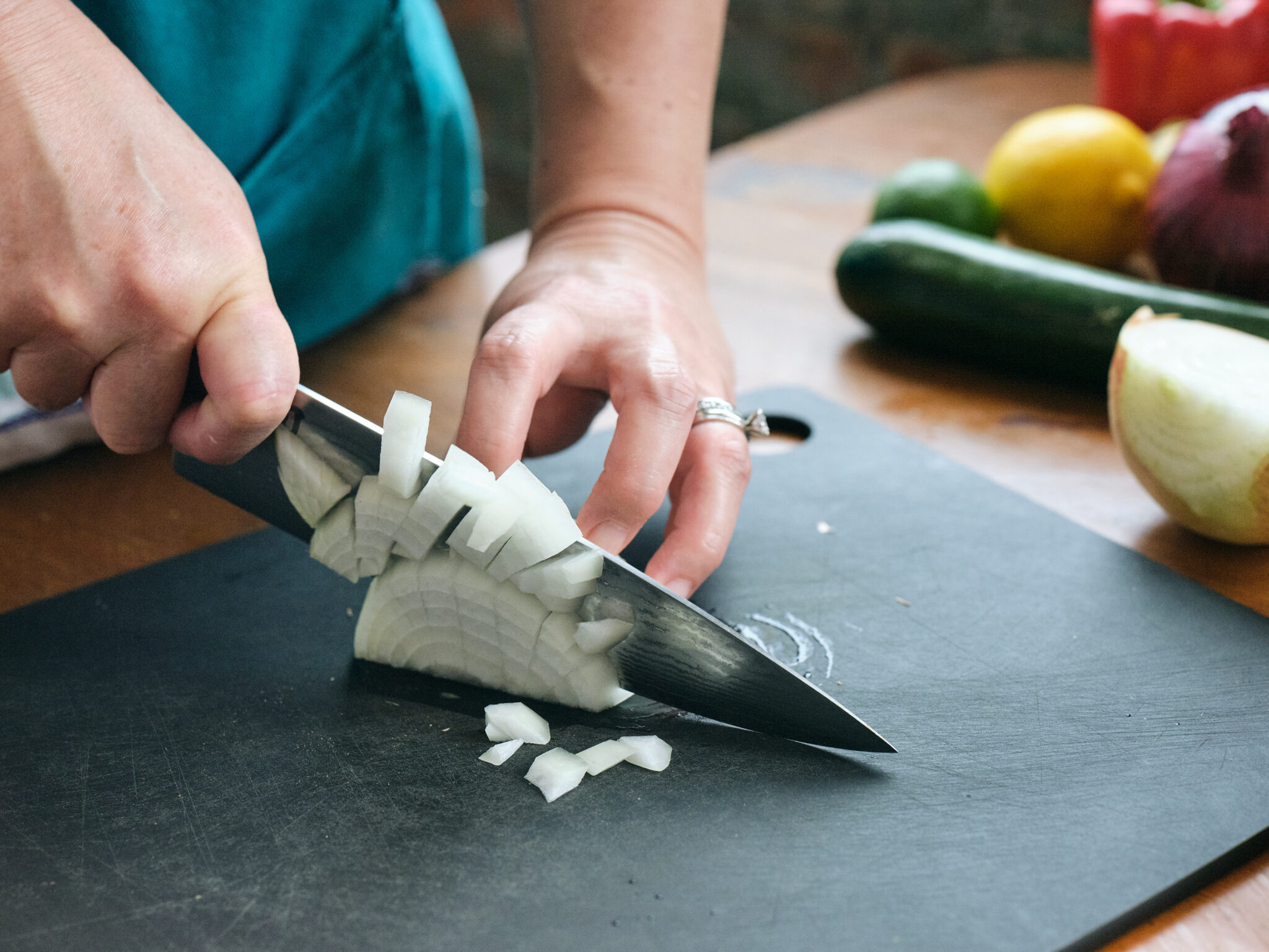 hands chopping onion on cutting board